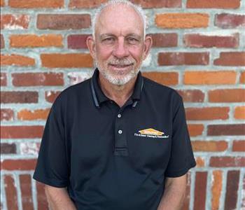 man in black polo shirt with SERVPRO logo standing in front of brick wall