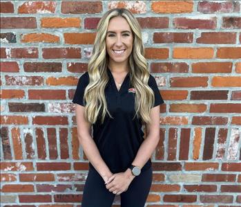 woman with black SERVPRO shirt standing in front of brick wall