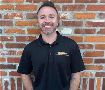 man in polo shirt with SERVPRO logo standing in front of brick wall