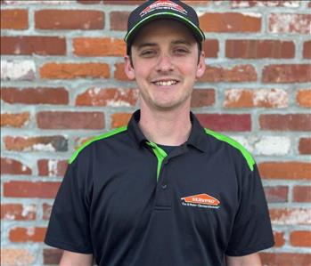 man with black hat and shirt with SERVPRO logos standing in front of brick wall