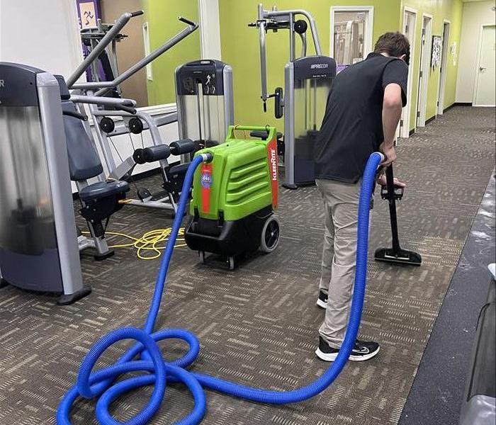 man extracting water from flooded gym carpet 